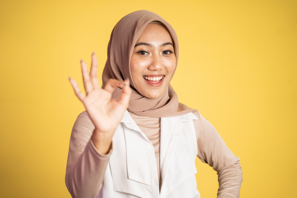 Asian Woman in Hijab Smiling with Okay Gesture